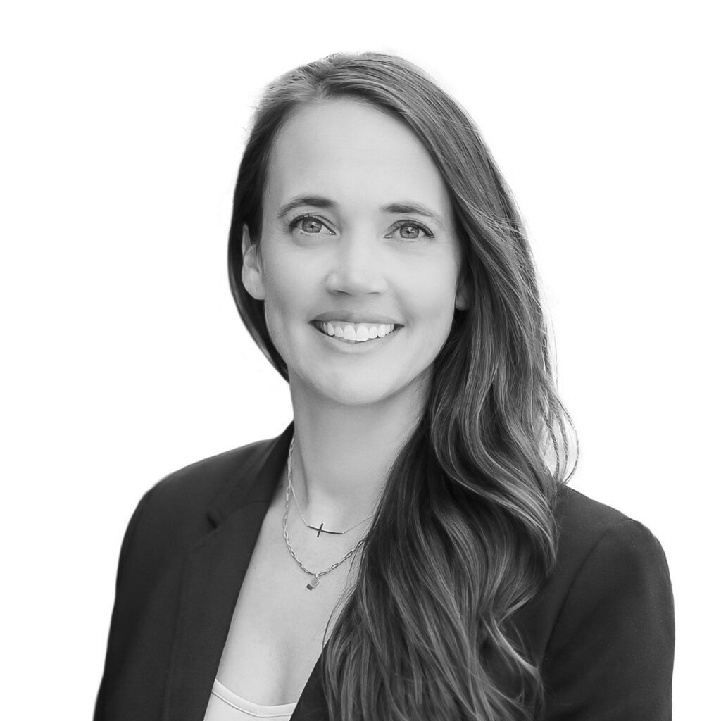 Professional headshot of a smiling woman in a blazer facing the camera, with long hair over one shoulder